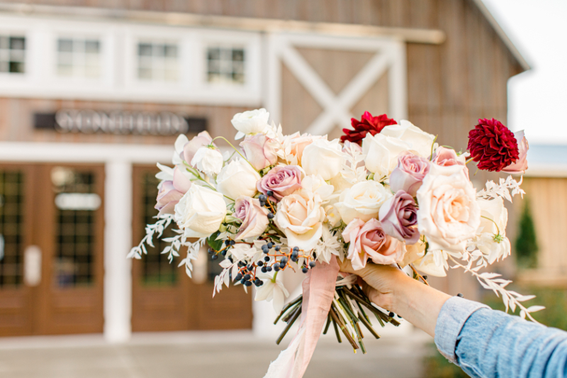 Holding up a bouquet outside a wedding venue